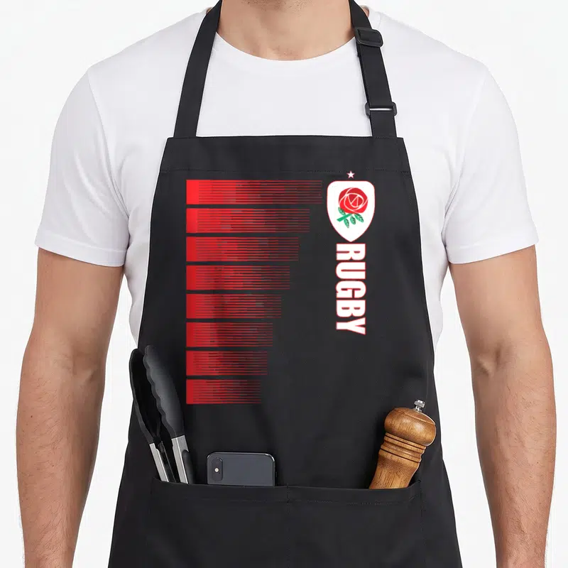 Tablier de cuisine noir avec rose rouge, blason blanc et texte vertical RUGBY en blanc.