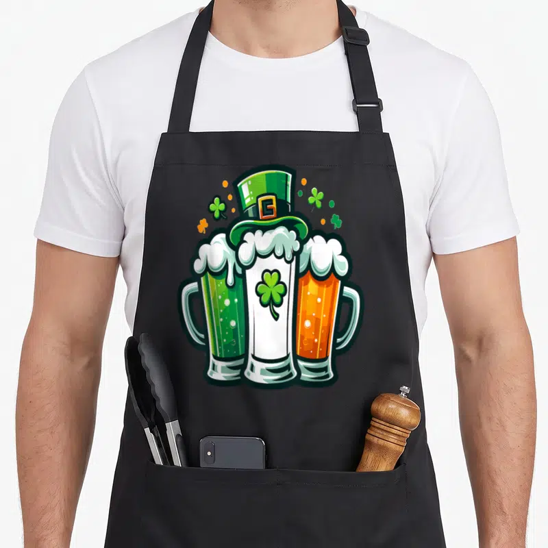 Tablier de cuisine noir avec illustration de trois verres de bière verts blancs et oranges surmontés d'un chapeau haut de forme vert.