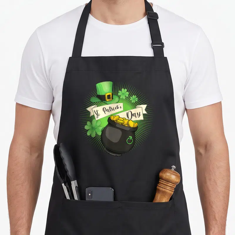 Tablier de cuisine noir avec illustration d'un chapeau vert, d'un pot de pièces d'or et de trèfles pour la Saint-Patrick.