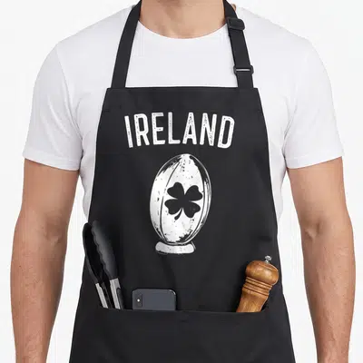 Tablier de cuisine noir avec l'inscription IRELAND et un ballon de rugby orné d'un trèfle noir en style vintage.