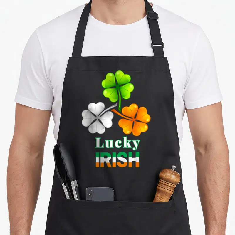 Tablier de cuisine noir avec trois trèfles colorés et le texte Lucky Irish aux couleurs du drapeau irlandais.