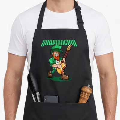 Tablier de cuisine noir avec lutin jouant d'une guitare électrique et le texte Shamrockin en vert.