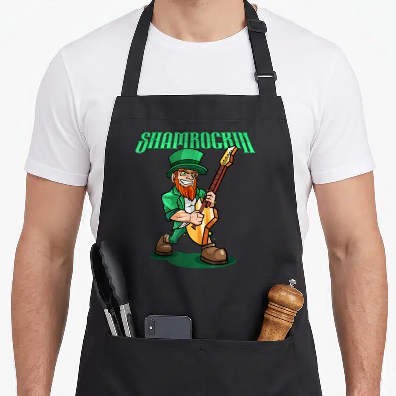 Tablier de cuisine noir avec lutin jouant d'une guitare électrique et le texte Shamrockin en vert.