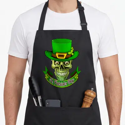 Tablier de cuisine noir avec un crâne vert coiffé d'un chapeau haut de forme vert et d'une banderole textée.