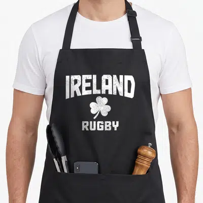 Tablier de cuisine noir avec linscription blanche IRELAND RUGBY surmontant un trèfle à quatre feuilles stylisé.