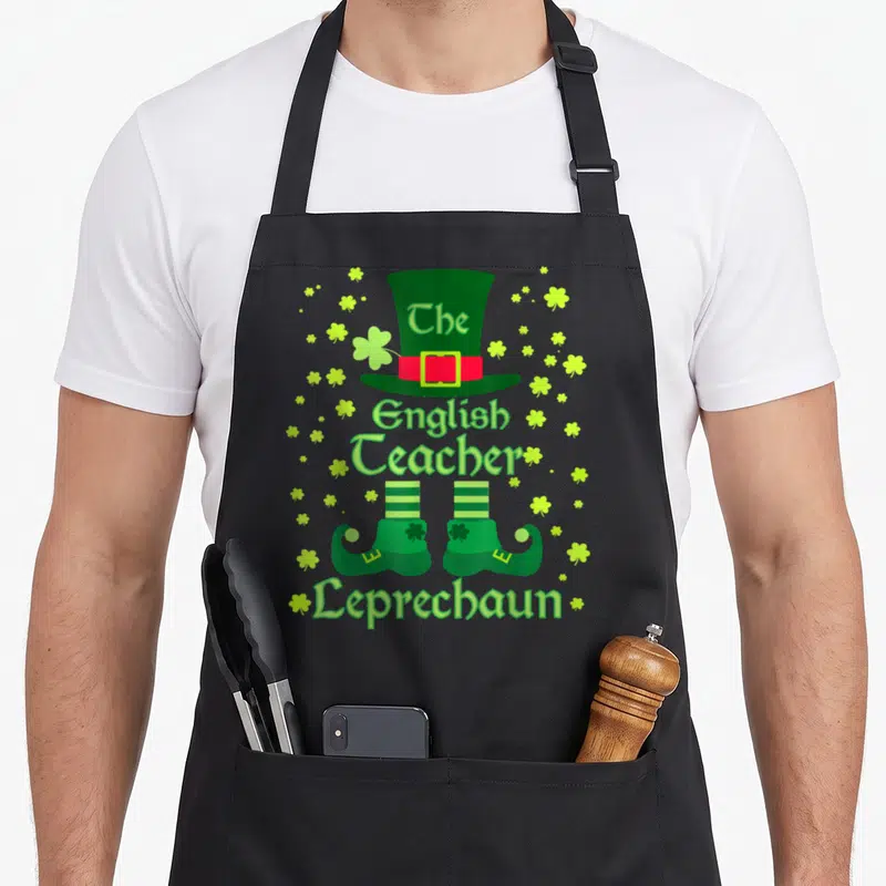 Tablier de cuisine noir avec illustration de lutin enseignant d'anglais coiffé d'un chapeau vert et entouré de trèfles.