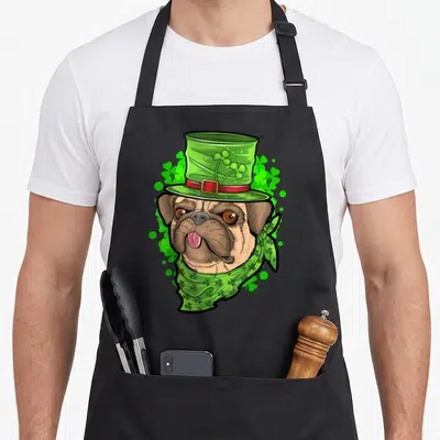 Tablier de cuisine noir avec un pug portant un chapeau de lutin vert orné de trèfles à quatre feuilles.