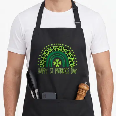 Tablier de cuisine noir avec arc-en-ciel motif léopard vert et texte Happy St Patrick's Day en bas.