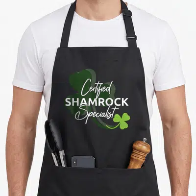 Tablier de cuisine noir avec un grand trèfle vert et l'inscription Certified Shamrock Specialist en blanc.