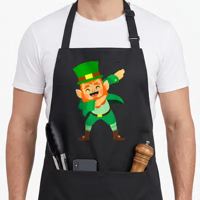 Tablier de cuisine noir avec un leprechaun aux cheveux roux effectuant une pose dab souriante.