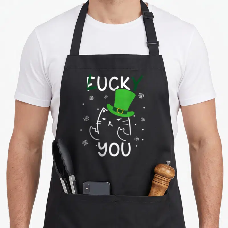Tablier de cuisine noir avec chat blanc au chapeau vert Lucky You et trèfles blancs.