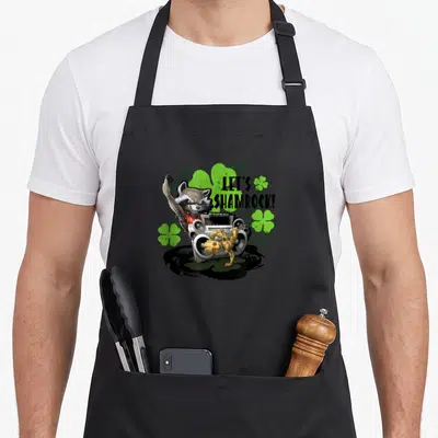 Tablier de cuisine noir avec Rocket Racoon, Groot et une boombox sur fond de trèfles verts.