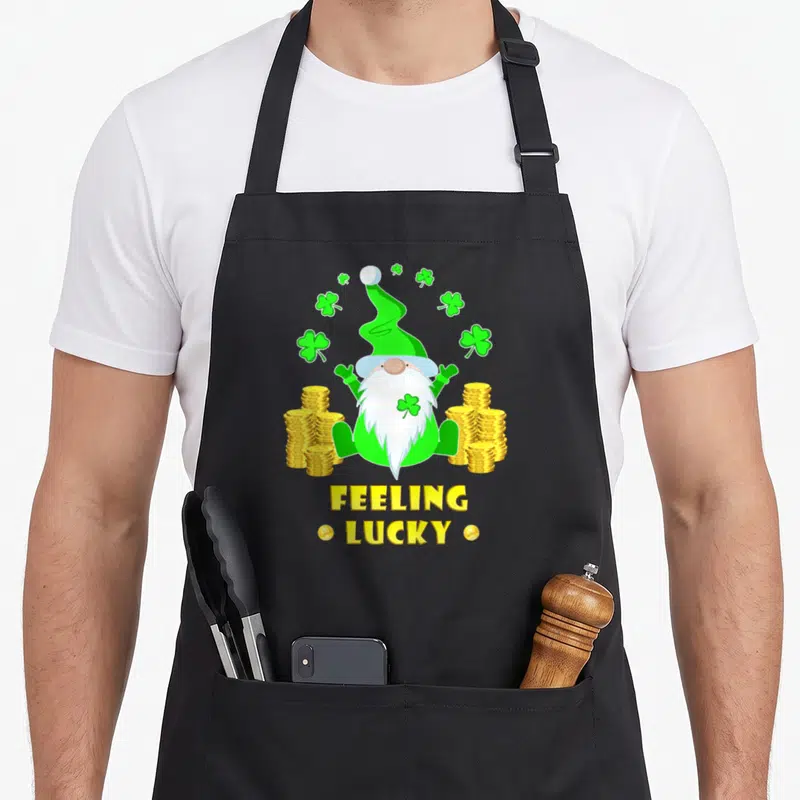 Tablier de cuisine noir avec illustration colorée d'un nain vert aux pièces d'or et trèfles verts.