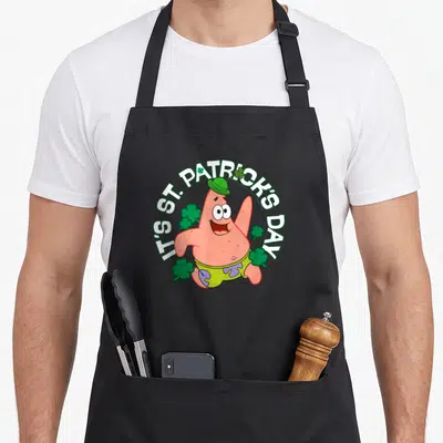 Tablier de cuisine noir avec Patrick en chapeau vert entouré de trèfles et du texte It's St. Patrick's Day.
