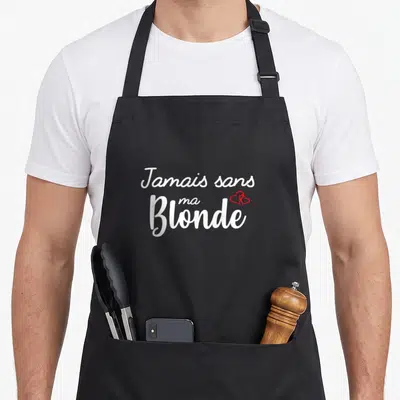 Tablier de cuisine noir avec l'inscription blanche Jamais sans ma Blonde et un petit cœur rouge stylisé sur le côté.