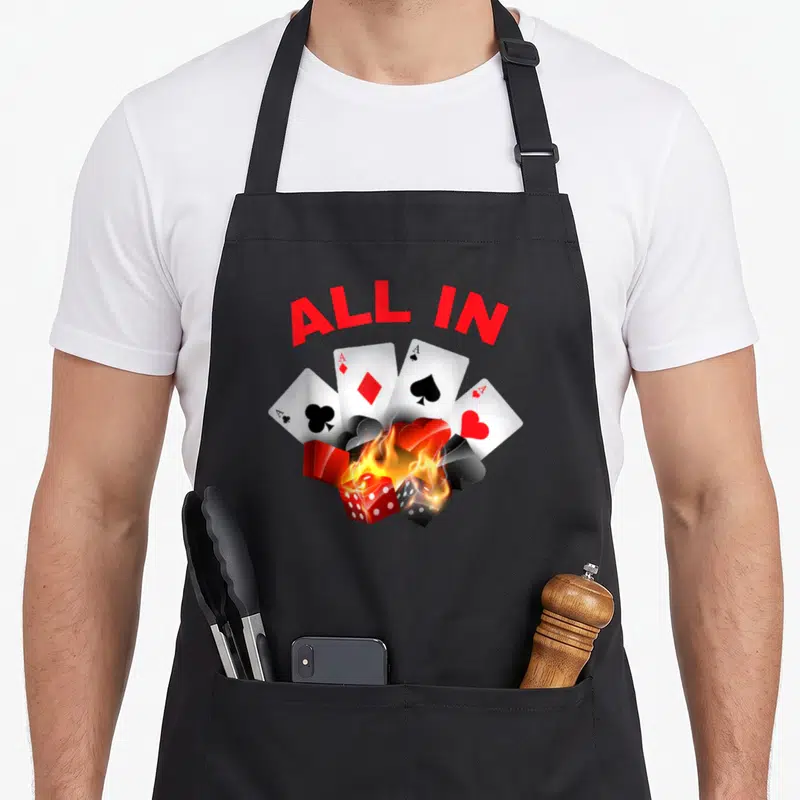 Tablier de cuisine noir avec illustration de cartes à jouer, dés enflammés et texte All In en rouge.