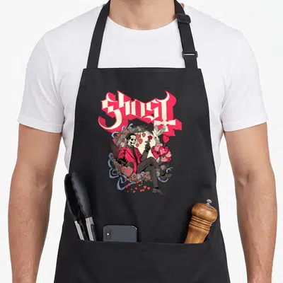 Tablier de cuisine noir avec un squelette en costume rouge tenant une rose, entouré de cœurs et de fleurs roses sous le mot Ghost.