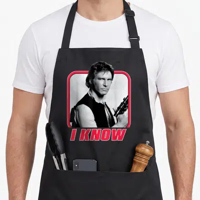 Tablier de cuisine noir avec portrait en noir et blanc de Han Solo encadré de rose et le texte I KNOW en bas.