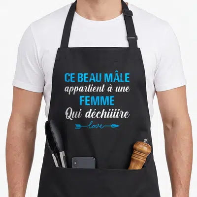 Tablier de cuisine noir avec inscription Ce beau mâle appartient à une femme qui déchiiire en bleu et blanc.