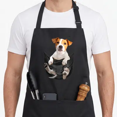 Tablier de cuisine noir avec un Jack Russell Terrier sortant d'une poche imprimée en couleur.