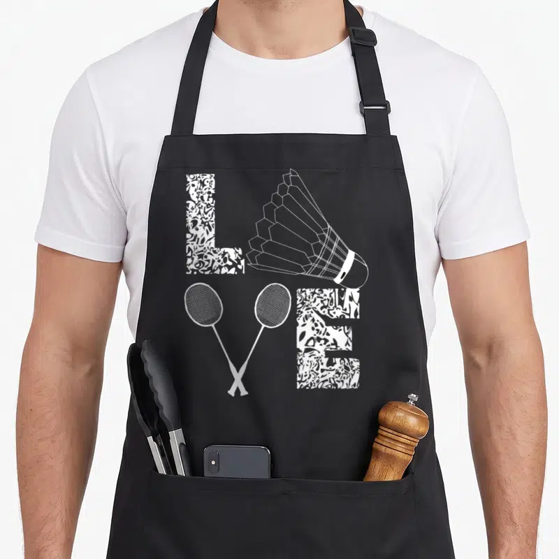Tablier de cuisine noir avec motif blanc représentant des raquettes croisées, un volant et les lettres LVE stylisées.