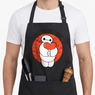 Tablier de cuisine noir avec Baymax tenant un cœur et l'inscription Would You Like A Hug sur fond orange.