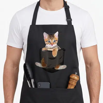 Tablier de cuisine noir avec un chat bengal mignon sortant d'une poche dessinée en illustration centrale.