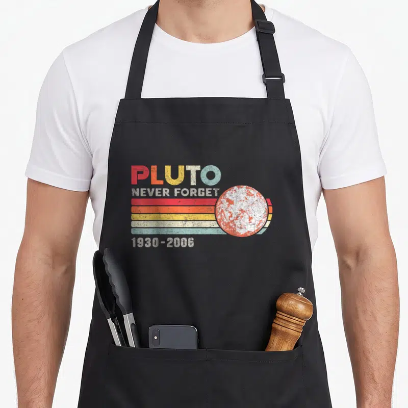 Tablier de cuisine noir avec motif retro Pluto Never Forget 1930-2006 et illustration de planète texturée.