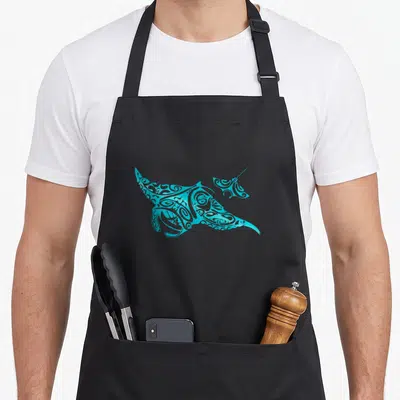 Tablier de cuisine noir avec une illustration tribale turquoise représentant deux raies manta en mouvement fluide sur fond uni.