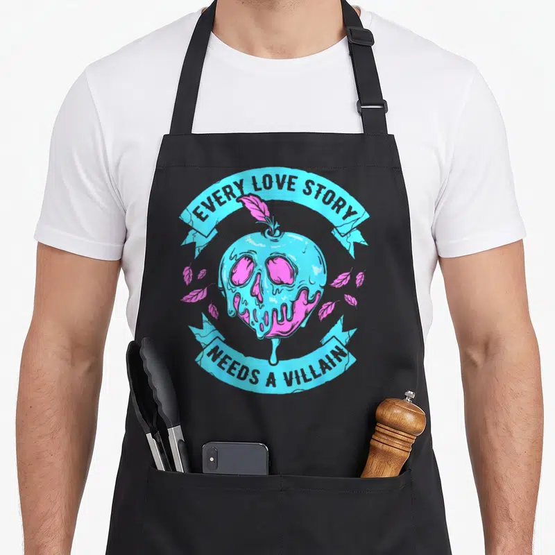 Tablier de cuisine noir avec une pomme empoisonnée stylisée en crâne rose et bleu, entourée de rubans textuels.