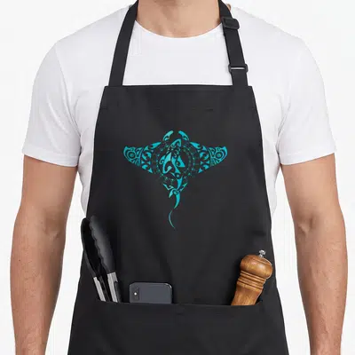 Tablier de cuisine noir avec une raie manta tribale turquoise stylisée au centre du torse.