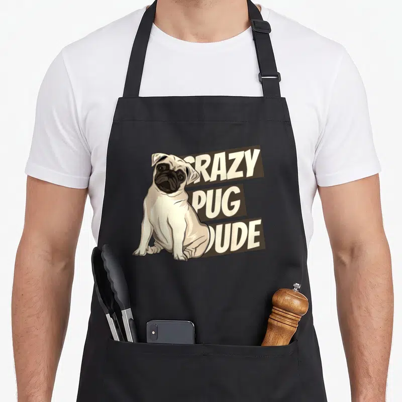 Tablier de cuisine noir avec illustration d'un pug assis et texte Crazy Pug Dude en lettres capitales blanches sur fond marron.
