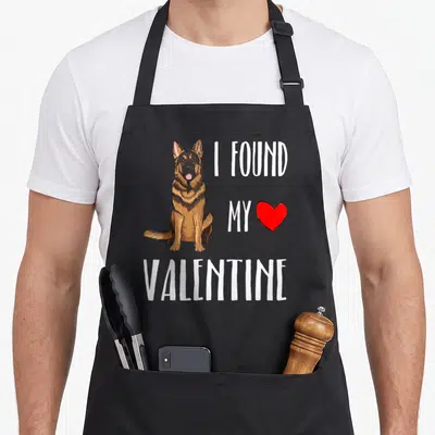 Tablier de cuisine noir avec illustration d'un Berger Allemand assis et texte blanc I FOUND MY VALENTINE accompagné d'un cœur rouge.