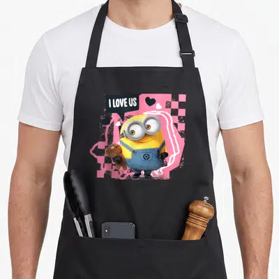 Tablier de cuisine noir avec Bob tenant un ours en peluche et le texte I Love Us sur fond rose à carreaux.