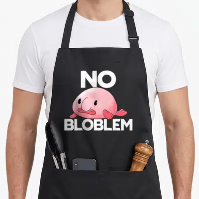 Tablier de cuisine noir avec illustration d'un blobfish rose et texte blanc No Bloblem centré.