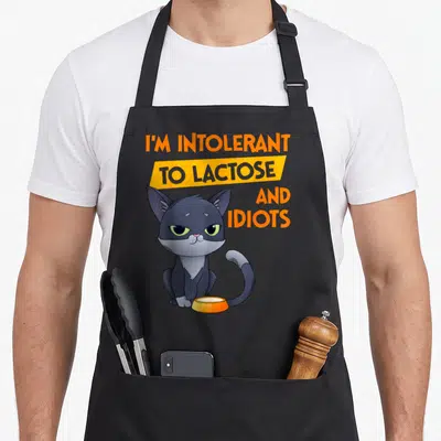 Tablier de cuisine noir avec un chat gris assis et le texte Je suis intolérant au lactose et aux idiots en orange et gris.
