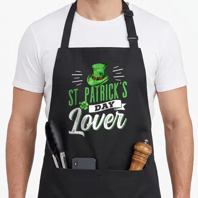Tablier de cuisine noir avec illustration chapeau vert Amateur de la Saint-Patrick et trèfle à quatre feuilles.