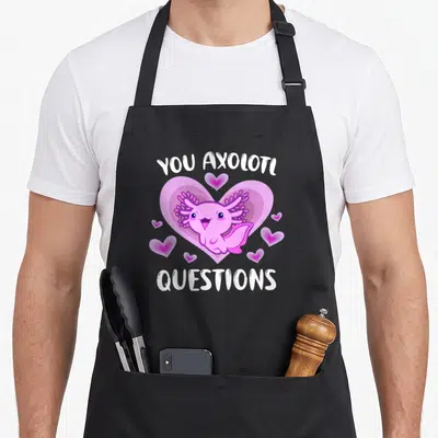 Tablier de cuisine noir avec un axolotl rose, des cœurs et le texte YOU AXOLOTL QUESTIONS imprimé en blanc.