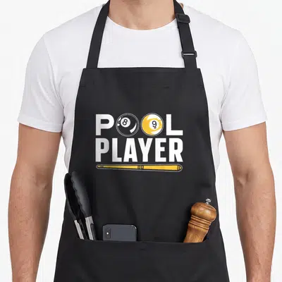 Tablier de cuisine noir avec le texte Pool Player et une illustration de boule 8, boule 9 et queue de billard jaune.