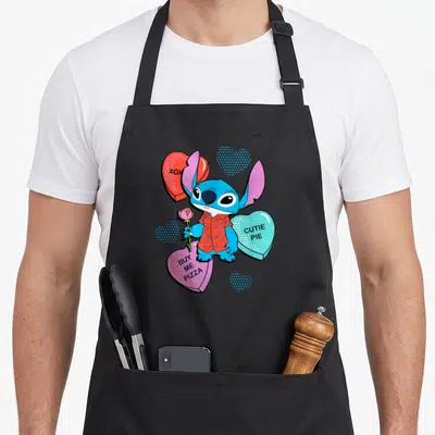 Tablier de cuisine noir avec Stitch tenant une rose entouré de cœurs sucrés aux couleurs vives.