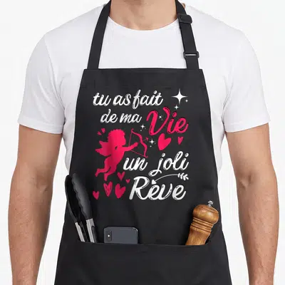 Tablier de cuisine noir avec inscription blanche et rose et silhouette de cupidon tirant une flèche.
