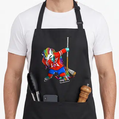 Tablier de cuisine noir avec illustration d'une licorne aux cheveux arc-en-ciel en tenue de hockey sur glace.