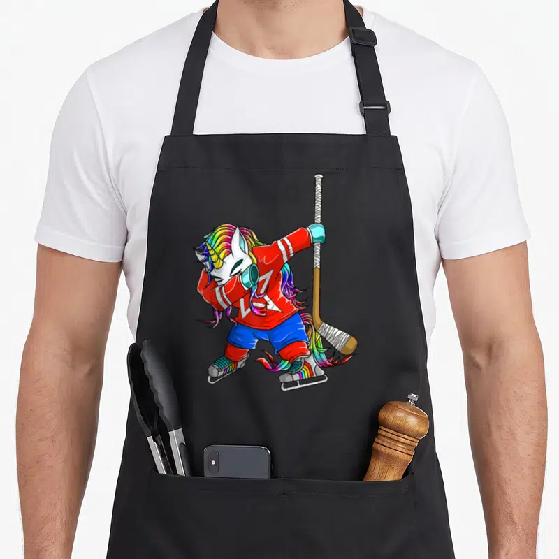 Tablier de cuisine noir avec illustration d'une licorne aux cheveux arc-en-ciel en tenue de hockey sur glace.