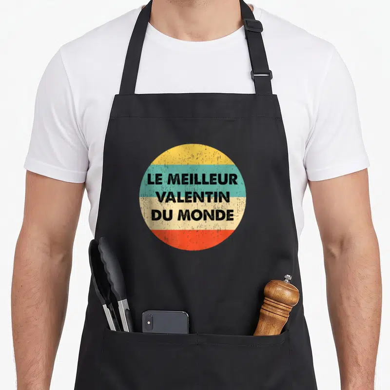Tablier de cuisine noir avec un cercle multicolore portant l'inscription le meilleur valentin du monde en lettres noires.