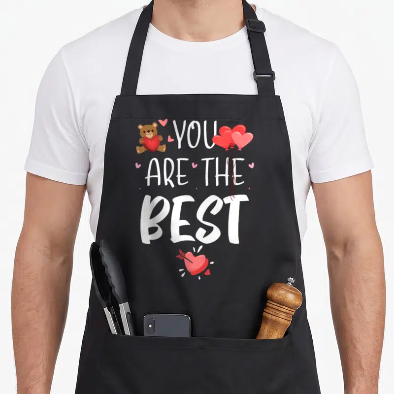 Tablier de cuisine noir avec inscription You Are The Best et ours tenant un cœur rouge.