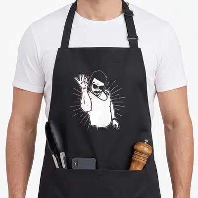 Tablier de cuisine noir avec illustration stylisée d'un homme aux lunettes de soleil et cœurs rouges sur le bras.