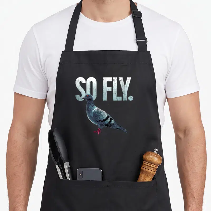 Tablier de cuisine noir avec illustration de pigeon et texte So Fly en lettres claires texturées.