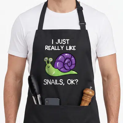 Tablier de cuisine noir avec un escargot violet et vert et le texte I just really like snails ok en blanc.