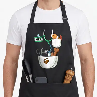 Tablier de cuisine noir avec illustration de poche blanche contenant un lapin, un stéthoscope, des ciseaux et une ossement.