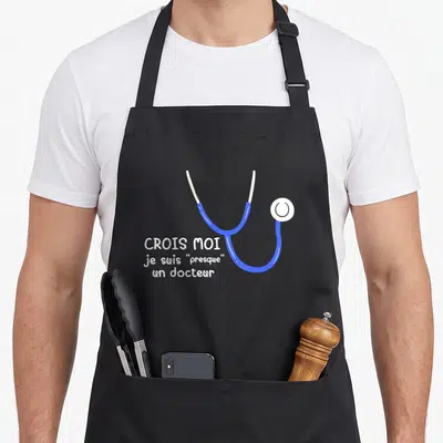 Tablier de cuisine noir avec illustration de stéthoscope bleu et texte blanc humoristique sur le thème médical.